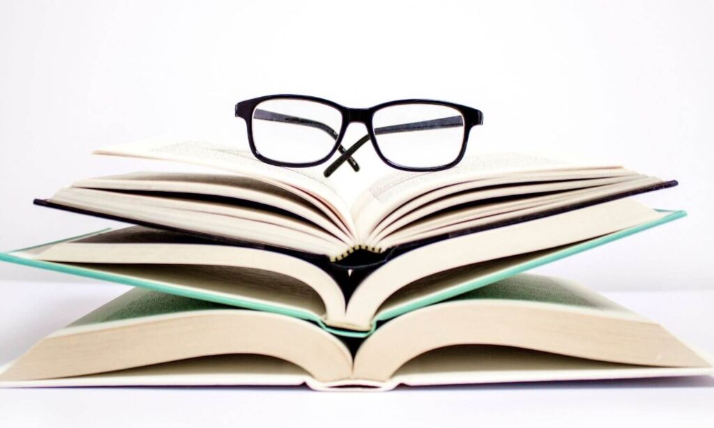 glasses laying on top of three books stacked together