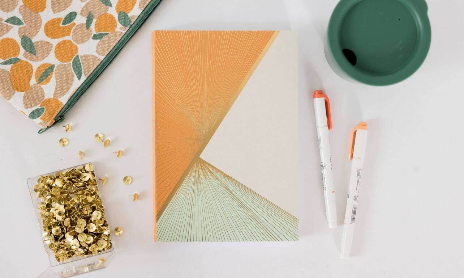 orange, cream, green journal on a desk
