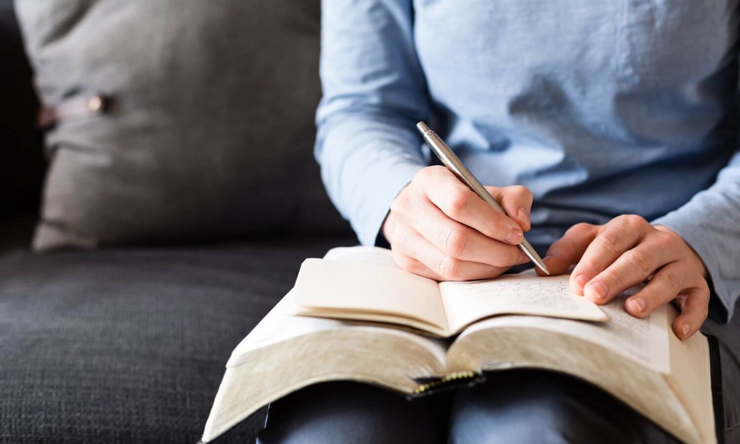 woman sitting on couch taking notes from the Bible in her lap